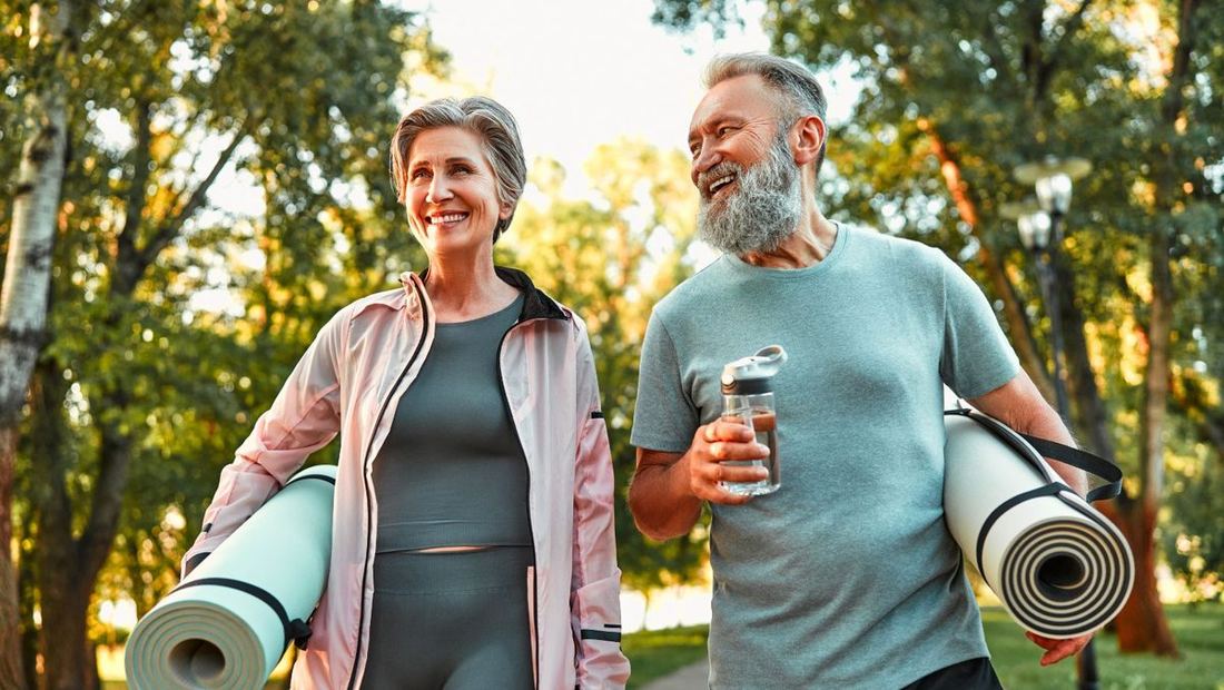 Two people outdoors carrying yoga mats