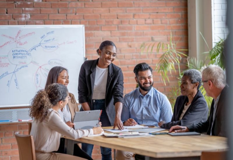 Colleagues in a workshop around a table with a whiteboard