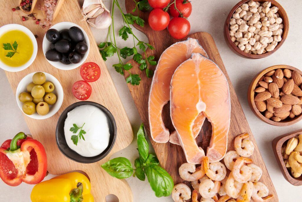 Salmon steaks, prawns, nuts, chickpeas, olives, mozzarella, tomatoes and peppers arranged on wooden boards