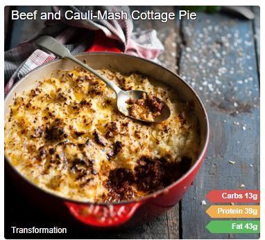 Beef cottage pie with golden cauliflower mash topping in a red casserole dish, with a spoon and nutrition labels