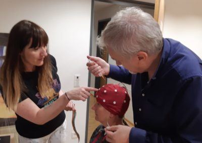 Two practitioners fitting an EEG cap on a seated person during neurofeedback preparation
