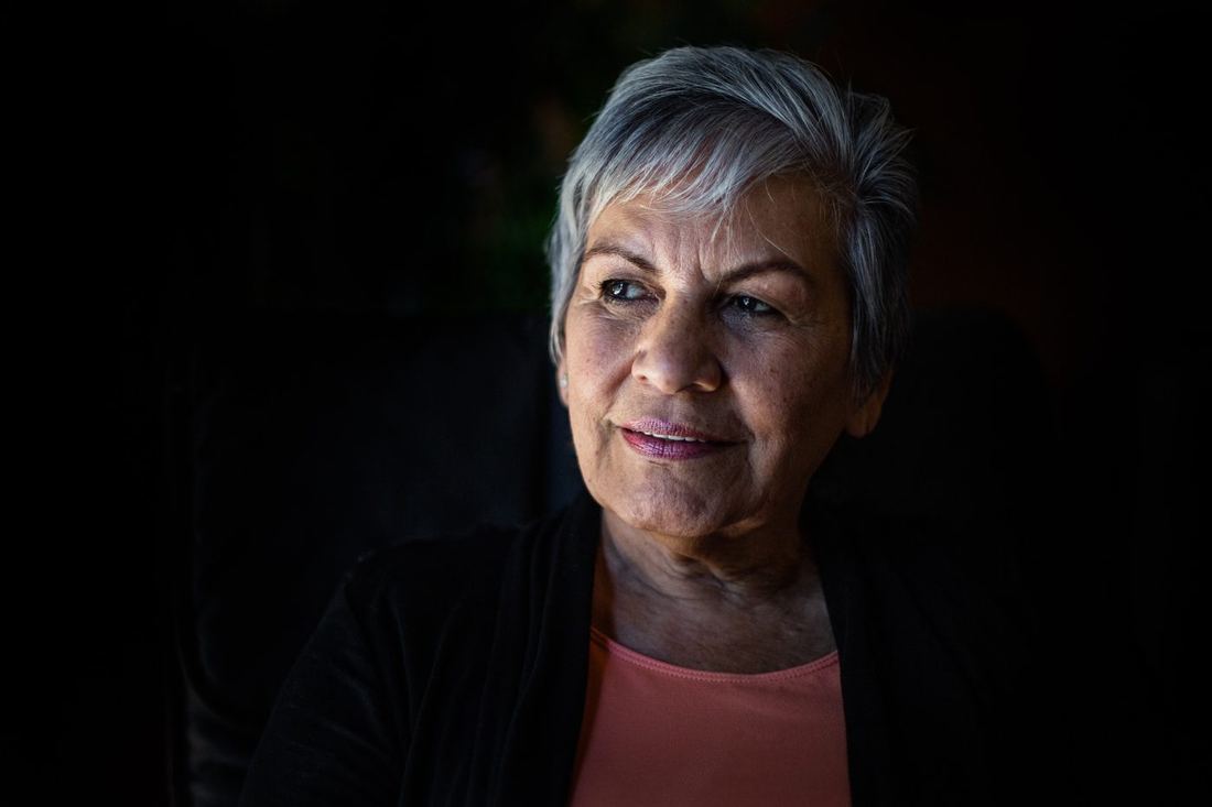An older woman with short grey hair, smiling thoughtfully
